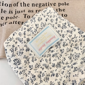 Macro detail of quilted floral camera pouch showing blue flowers and cotton texture