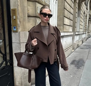 Détail d'un manteau en laine marron foncé avec un grand sac à main en cuir assorti