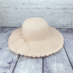 Detail of beige wide brim straw hat with scalloped edges and delicate bow tie detail