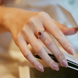 Vintage red gemstone ring with diamond halo and rose gold finish on hand
