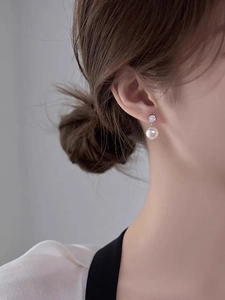 Detailed view of silver needle pearl earrings with sparkling zircon on a female model