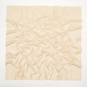 Macro detail of beige matte satin silk scarf showcasing soft texture and luxury luster