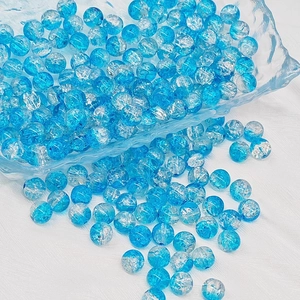 Macro shot of blue and clear crackle glass beads in a glass bowl for DIY jewelry making