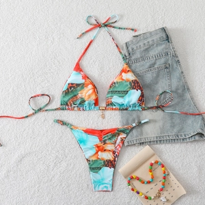 Flat lay of a vibrant tropical bikini with halter top and starfish charm on white plush background