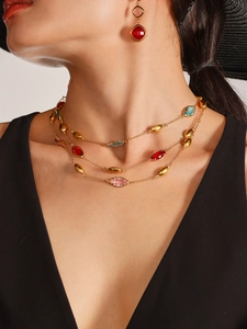 Close-up of layered gold chain necklace with colorful faceted water-drop glass stones
