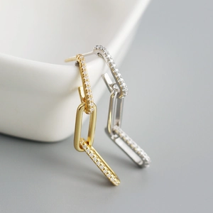 Detail of geometric chain earrings featuring pavé rhinestones in gold and silver finish