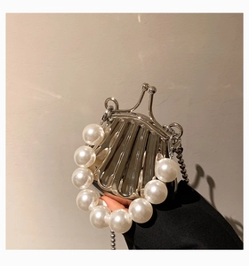 Detail einer silbernen Mini-Tasche in Muschelform mit Perlengriff und Metallkette