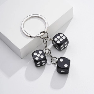 Close-up of black metal dice charms with white dots on a keychain with a link chain