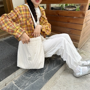 Off-white pleated canvas bag on model highlighting textured fabric and large capacity
