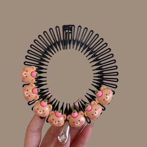 Close-up of black hair comb with cute pink bear and peach ornaments for kids