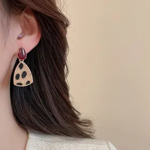 Detailaufnahme von Ohrringen mit Leopardenmuster und roten Steinen an einem Modell