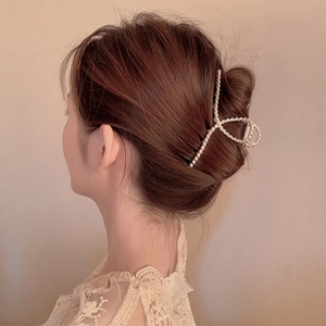 Detailed close-up of large criss-cross hair claw clip with pearl-embellished surface