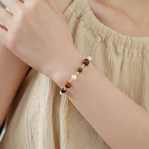 Beaded gold plated bracelet featuring pearls and tiger eye stones on a model wrist