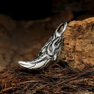 Rugged silver stainless steel wolf tooth pendant with flame pattern on wood background