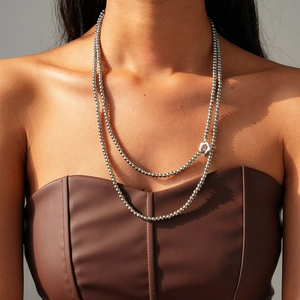 Detail of silver beaded necklace with floral toggle clasp worn on leather clothing
