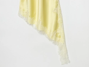 Dettaglio dell'abito in raso giallo chiaro con delicato bordo in pizzo a ciglia bianco