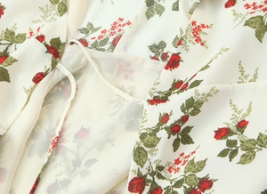 Close-up of red rose floral print on white chiffon fabric with waist tie detail