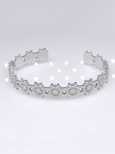 Macro detail of silver daisy floral patterns on a polished stainless steel open bangle