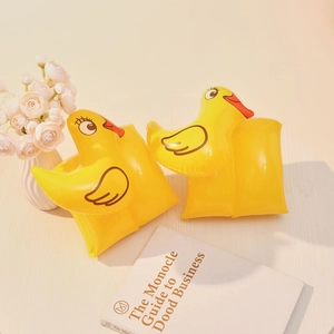 Detail of yellow inflatable duck arm floaties for kids swimming on a wooden surface
