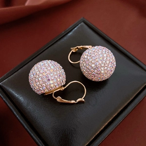 Macro shot of colorful rhinestone spheres on gold lever-back earrings with silk background