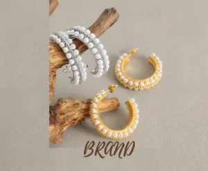 Detailed shot of C-shaped gold and silver hoop earrings with multiple rows of white pearls