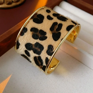Close-up of leopard print pony hair wide cuff bracelet with gold metal edges in a gift box