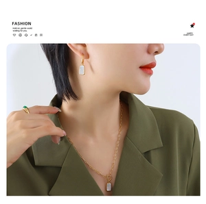 Ensemble de bijoux dorés avec collier pendentif nacre et boucles d'oreilles sur mannequin