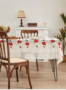 Close-up of white lace tablecloth featuring red Christmas flower embroidery and wavy edges