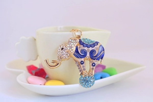 Detail of a golden flying elephant keychain with blue enamel and sparkling rhinestones