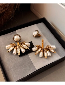 Vue détaillée de boucles d'oreilles vintage dorées avec perles et cristaux en boîte
