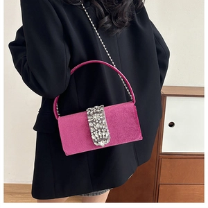 Detail of rose red velvet handbag with sparkling rhinestone buckle and silver chain strap