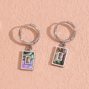 Detail of silver drop earrings featuring natural abalone shell and rectangle zircon inlay