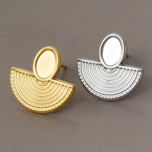 Detail of retro fan-shaped textured earrings in gold and silver finish on grey fabric