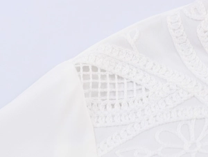 Close-up of white long sleeve shirt with intricate lace hollow and floral embroidery detail