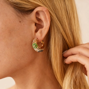 Détail de créoles dorées avec perles et perles vertes portées par un mannequin