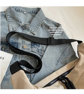 Detail of beige nylon crossbody bag with smooth black zipper and adjustable strap