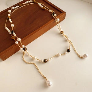 Detail of vintage necklace with pearls, tiger eye stones, and gold chain on wooden tray