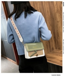 Detail of color-block crossbody bag with floral woven strap and green leather flap
