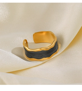 Detailed macro shot of irregular wavy gold ring with black enamel on silk background