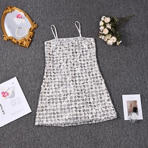 Détail d'une mini robe argentée à paillettes avec fines bretelles et accessoires de fête