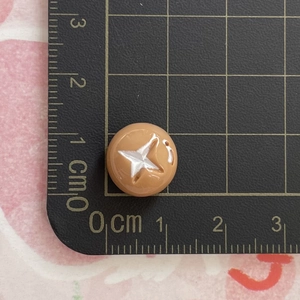 Detailed view of a 1.2cm brown miniature resin food charm with white star pattern