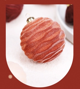 Close-up of orange flocked Christmas ball with wave texture and gold loop