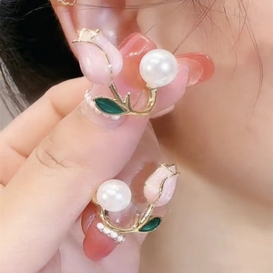 Detailed view of pink enamel tulip earrings with large white pearls and gold-plated finish