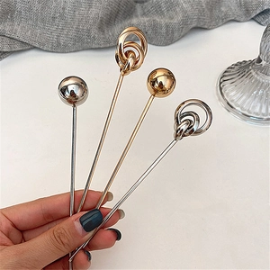 Detail view of four gold and silver geometric hair pins with ring and ball accents