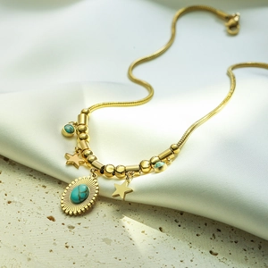 Gold snake chain necklace with turquoise sunburst pendant and star charms on silk