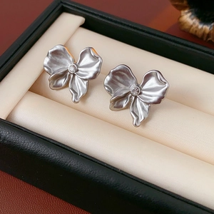 Macro shot of silver bow stud earrings with sparkling center stones in a jewelry box