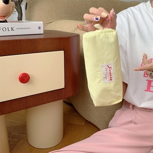 Handheld view of a compact yellow macaron-style fabric storage pouch with a zipper