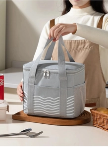 Close-up of grey lunch bag with white wave pattern and side mesh pocket in kitchen setting