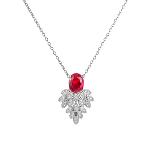 Macro detail of silver necklace with oval red gemstone and pavé leaf-shaped accents