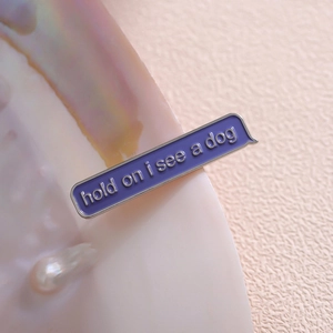 Purple enamel pin with 'hold on i see a dog' quote on a lustrous shell background